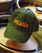 Load image into Gallery viewer, Green cap with 'VILLAGES' text on a metallic surface
